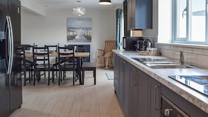 A modern kitchen with a marble countertop, stainless steel appliances, and a dining area with wooden chairs and a table.