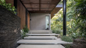 Eine Betontreppe führt zu einem modernen Gebäude mit Holzboden und einer Glastür.