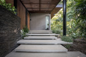 Eine Betontreppe führt zu einem modernen Gebäude mit Holzboden und einer Glastür.