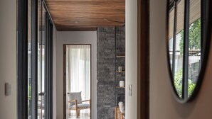 Ein moderner Flur mit Holzbalkendecke, Steinwand und Blick auf einen Balkon mit einem Sessel.