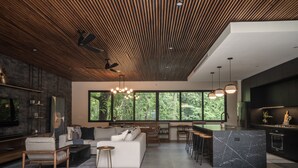 Eine moderne Küche mit einer großen Kochinsel, Barhocker und einem Essbereich mit einem weißen Sofa und Couchtisch.