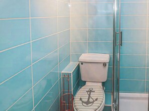 A bathroom with a toilet, a glass shower enclosure, and blue tiled walls.