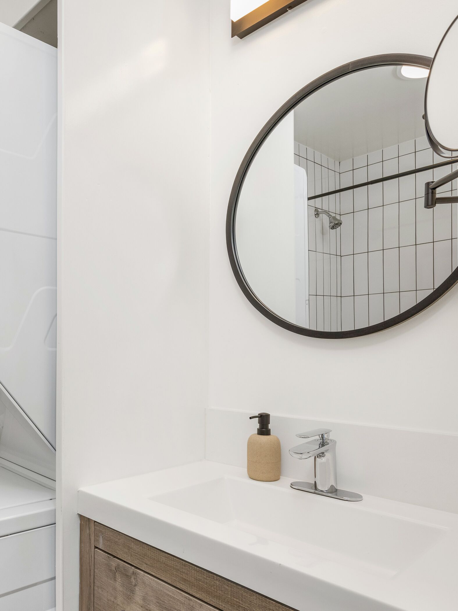 A bathroom with a white sink, a round mirror, and a shower.