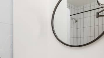 A bathroom with a white sink, a round mirror, and a shower.