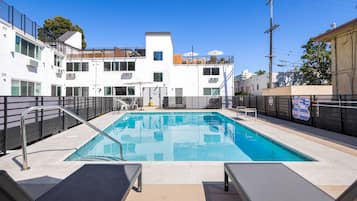 Una piscina al aire libre, sillones reclinables de piscina