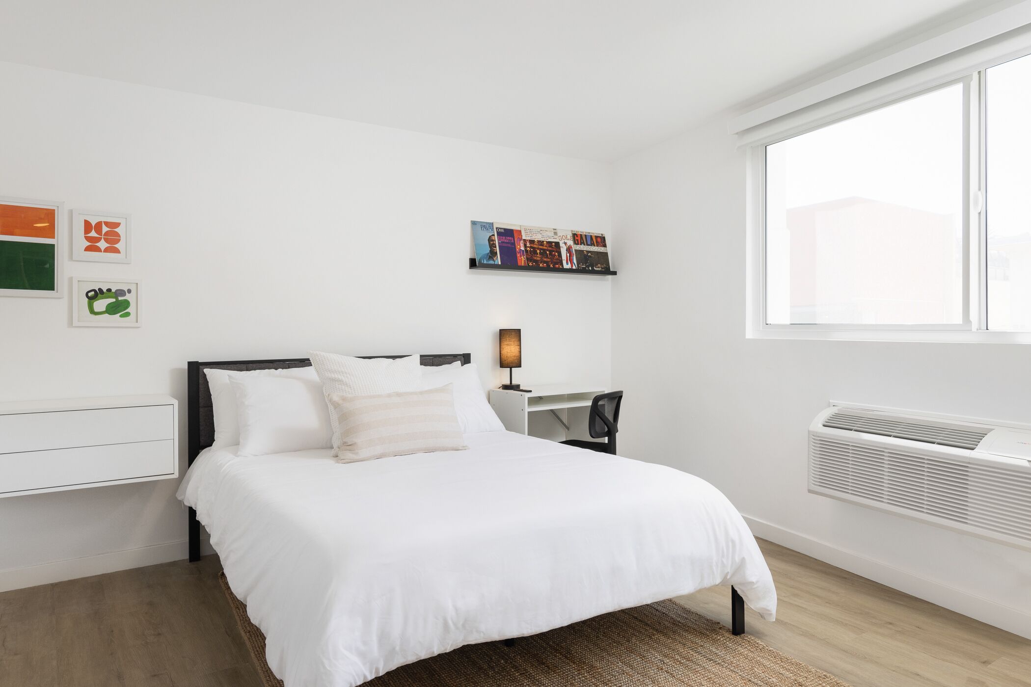 A modern bedroom with a bed, a desk, and a window.