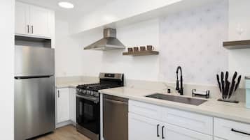 A modern kitchen with stainless steel appliances, white cabinetry, and a patterned backsplash.