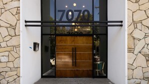 A modern building entrance with a large wooden door and the number 7070 displayed above. - Fenix Hotel Hollywood (Los Angeles)