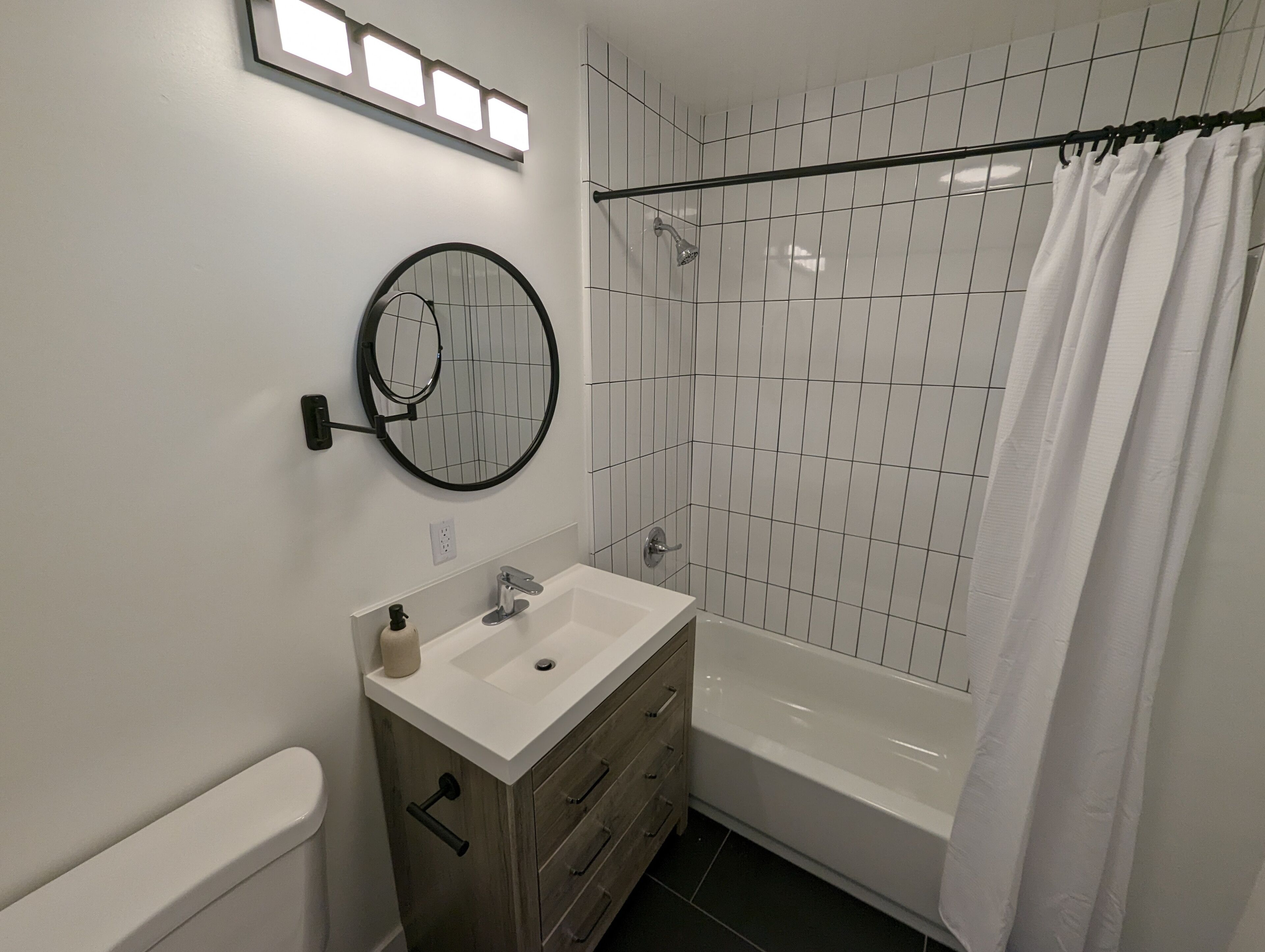 Un baño moderno con lavamanos, tocador y bañera blancos.