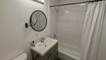 Un baño moderno con lavamanos, tocador y bañera blancos.