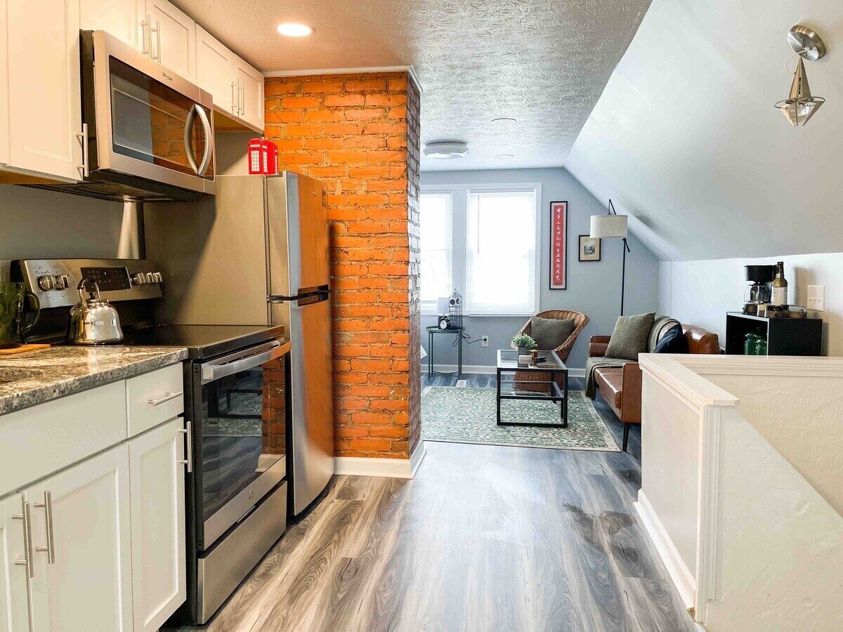 A kitchen with white cabinets, a brick accent wall, and a dining area with a sofa and table.