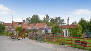 A traditional building with a red-tiled roof, a wooden fence, and flower beds in front. - 2 bedroom accommodation in Willoughton (Willoughton)