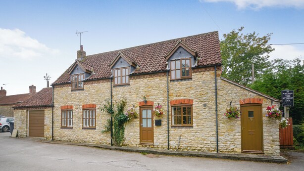 A stone building with a tiled roof, multiple windows, and a sign for 'The Stirrup Inn'. - 2 bedroom accommodation in Willoughton (Willoughton)