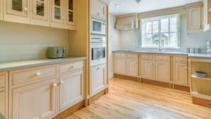 A kitchen with wooden cabinets, a built-in oven, a microwave, and a window with a view of the outside. - 2 bedroom accommodation in Willoughton (Willoughton)