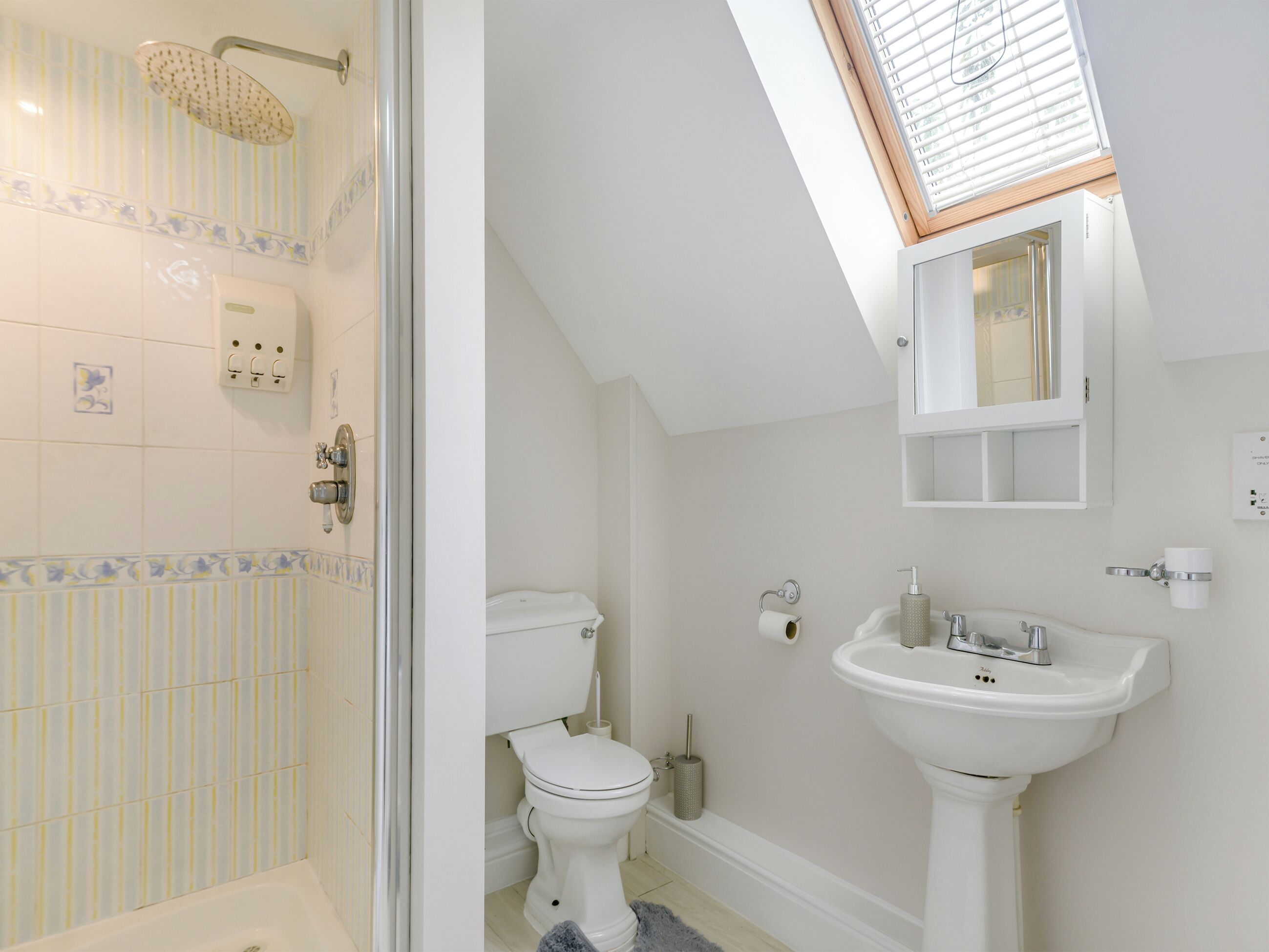 Een badkamer met dakraam, toilet, wastafel en douche.