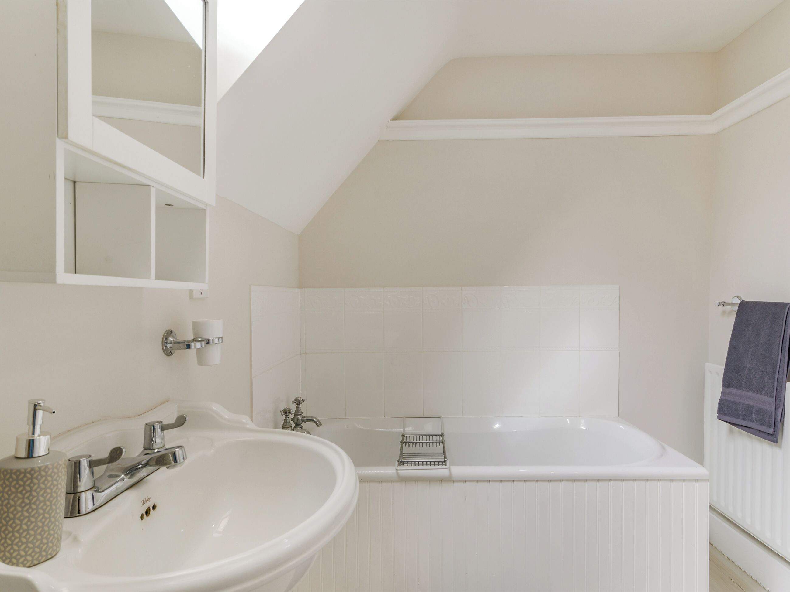 A bathroom with a white sink, a bathtub, and a mirror.