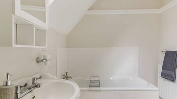A bathroom with a white sink, a bathtub, and a mirror.