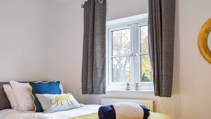 Une chambre à coucher avec un lit, une fenêtre avec des rideaux et un radiateur.