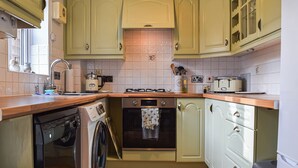 Une cuisine de taille réduite équipée d’un lave-linge, d’une cuisinière et d’un évier.