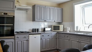A modern kitchen with grey cabinets, a built-in oven, a microwave, and a dishwasher. - 3 bedroom accommodation in Castle Douglas (Castle Douglas)