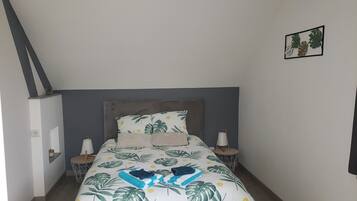 A bedroom with a bed, nightstands, a wall-mounted shelf, and a small wall decoration.