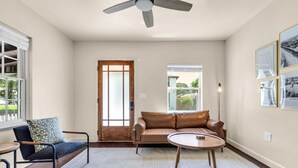 A spacious living room with a leather sofa, a round coffee table, and a high ceiling fan. - Discounted long stays- Located near St Pete beaches, downtown Gulfport (Gulfport)