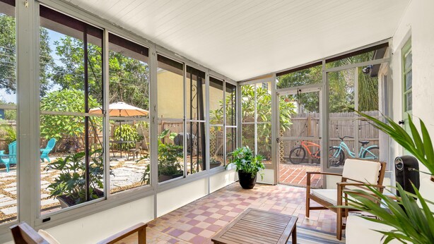 A sunlit patio with a checkered floor, large windows, and outdoor furniture. - Discounted long stays- Located near St Pete beaches, downtown Gulfport (Gulfport)