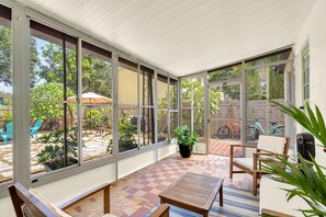 Un patio soleado con suelo a cuadros, ventanas amplias y mobiliario exterior.