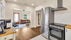 A modern kitchen with a stainless steel refrigerator, oven, and stove, wooden flooring, and a view to a living area with a sofa and chairs. - Discounted long stays- Located near St Pete beaches, downtown Gulfport (Gulfport)