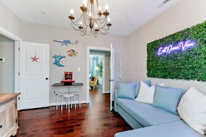 A living room with a blue sofa, a chandelier, and a neon sign on the wall.