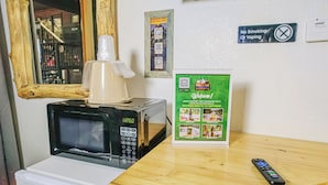 A microwave, a coffee maker, a remote control, and a welcome sign on a wooden table. - Spacious Lower-Level Hotel Queen and Full-size beds with Views 108-110 (Estes Park)