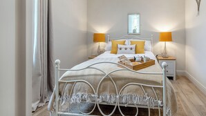 Un dormitorio ordenado con una cama, dos lámparas de noche, una ventana y una mesita de noche con una bandeja.