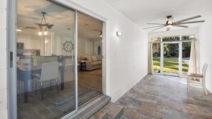 Un interior moderno con comedor, cocina y un patio con ventilador de techo y vistas al exterior.