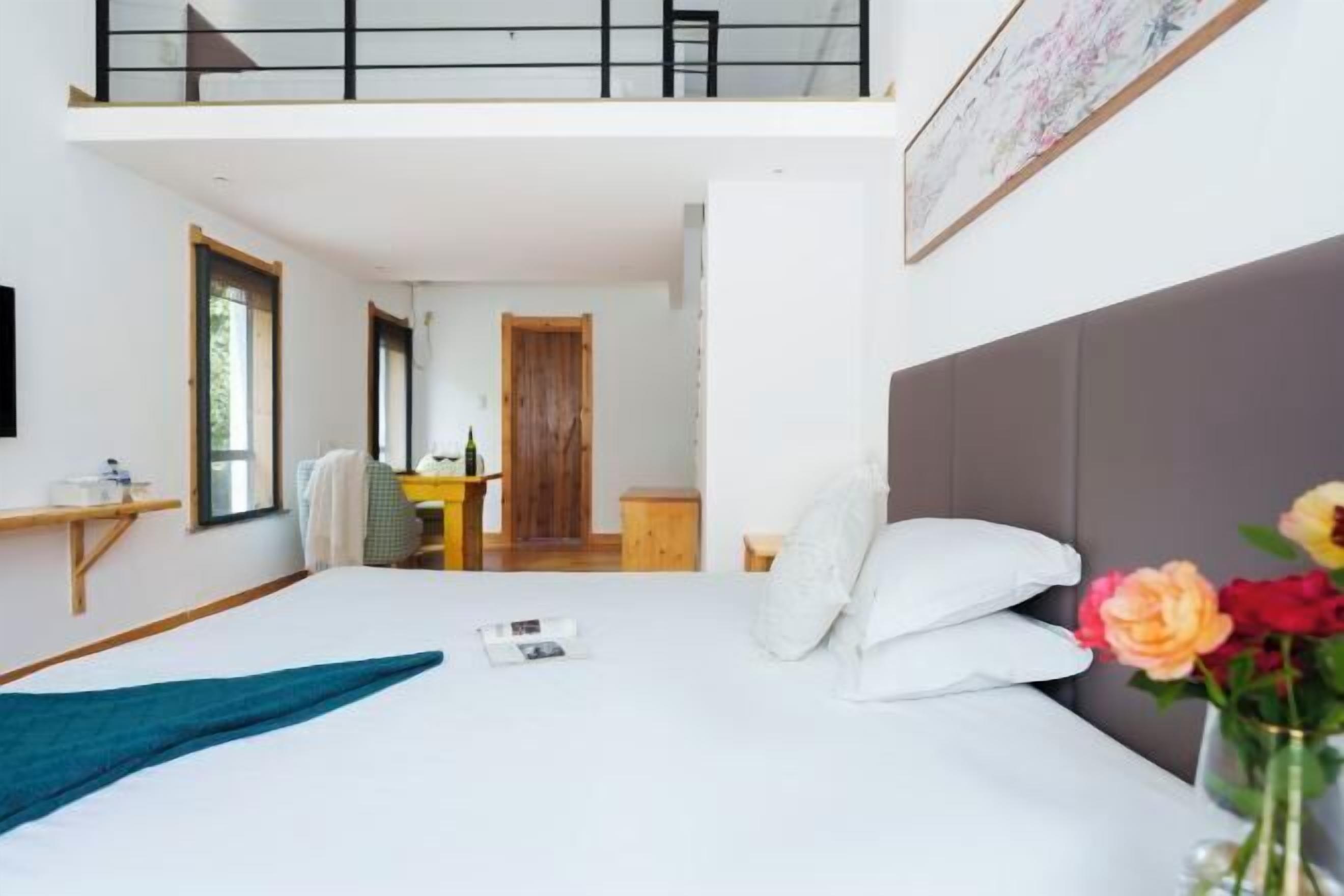 A hotel room with a bed, a desk, a chair, a window, and a balcony.