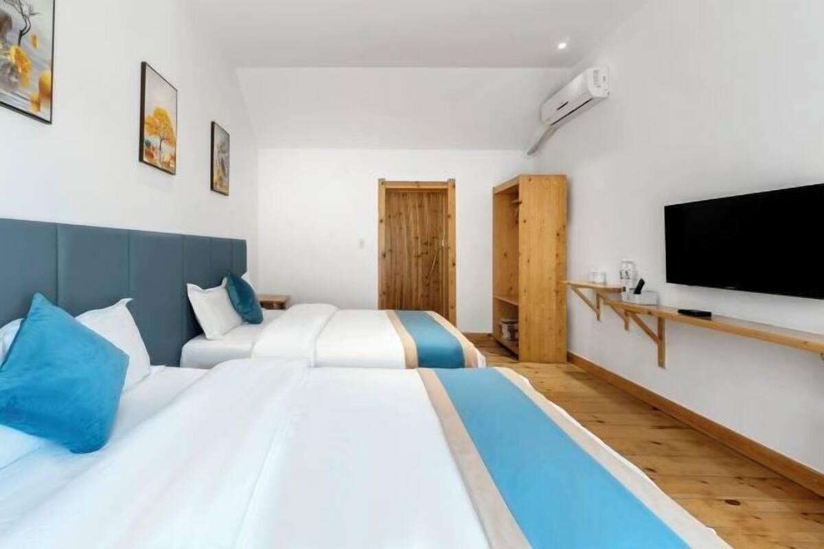 Habitació d'hotel amb dos llits, una televisió i un armari.