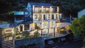 A modern two-story house with a glass balcony, a stone wall, and a staircase leading to the upper level. - Mojia Inn (Deqing)