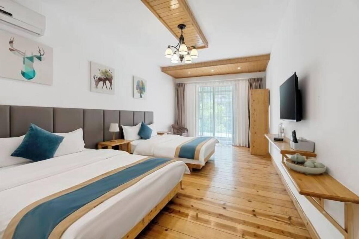 Habitació d'hotel amb dos llits, terra de fusta, televisió i obres d'art a les parets.