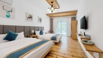 A hotel room with two beds, a wooden floor, a television, and artwork on the walls.