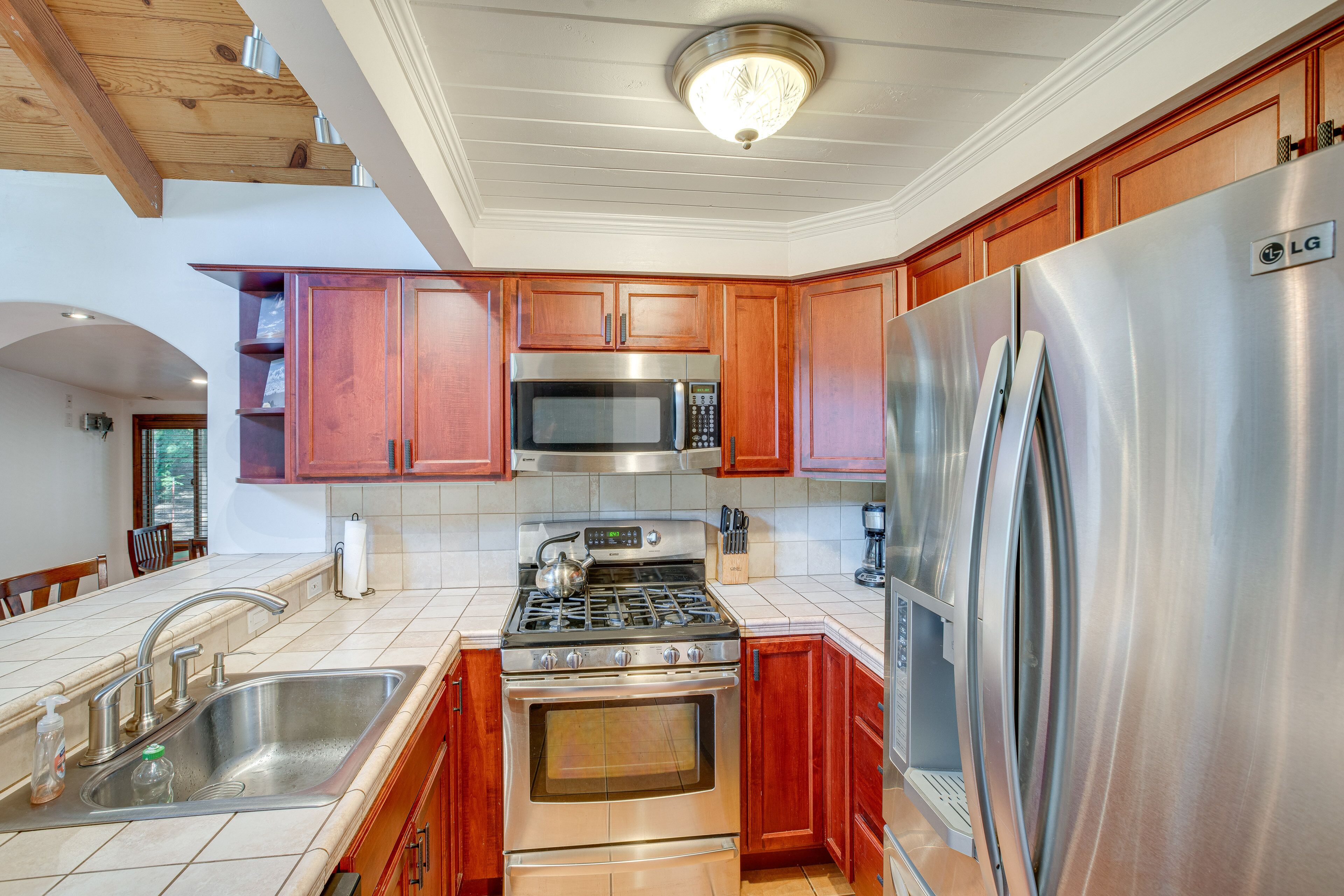 A kitchen with wooden cabinets, stainless steel appliances, a sink, and a ceiling light fixture.