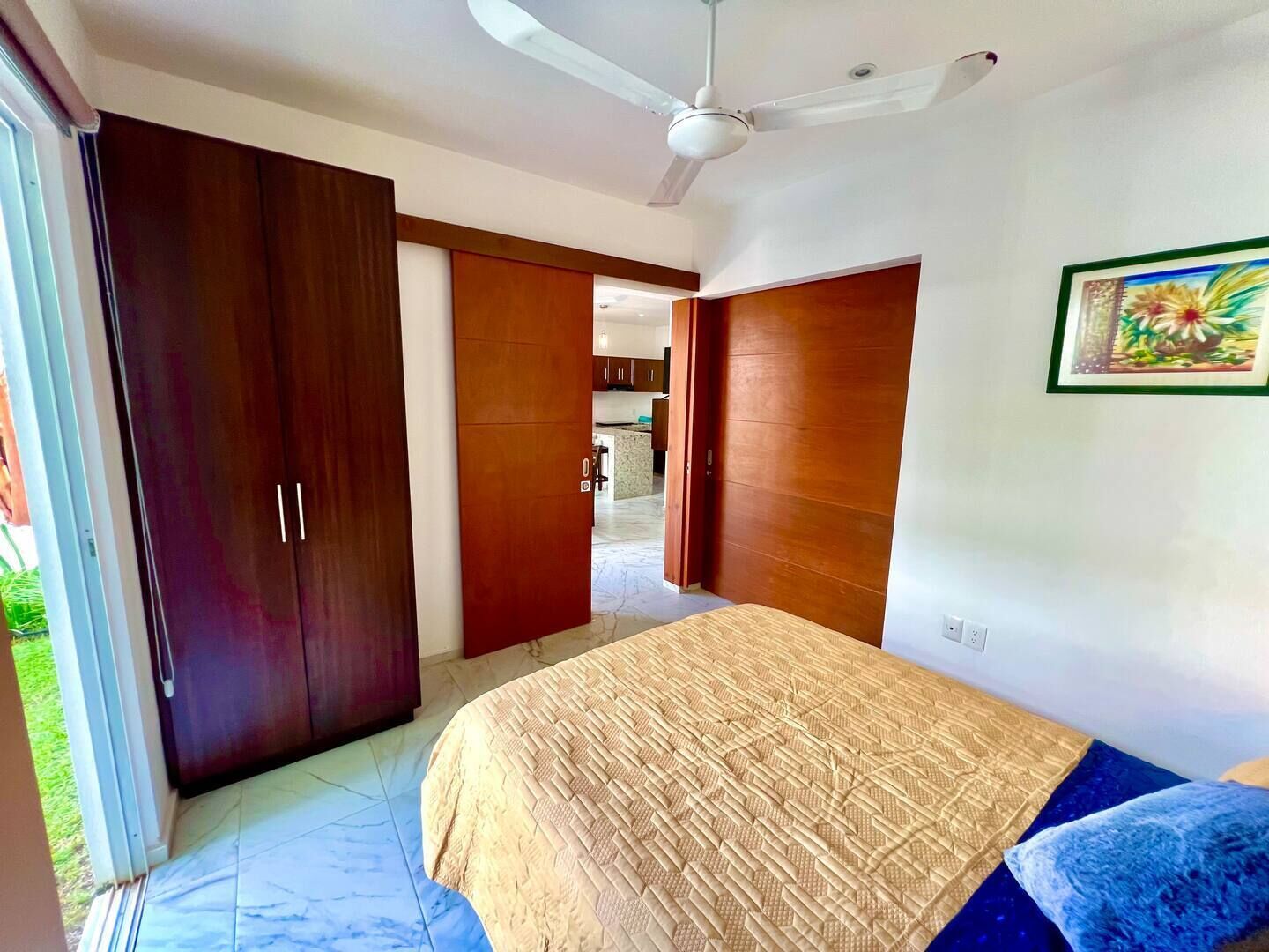 Un dormitorio con cama, ventilador de techo y un amplio armario de madera.