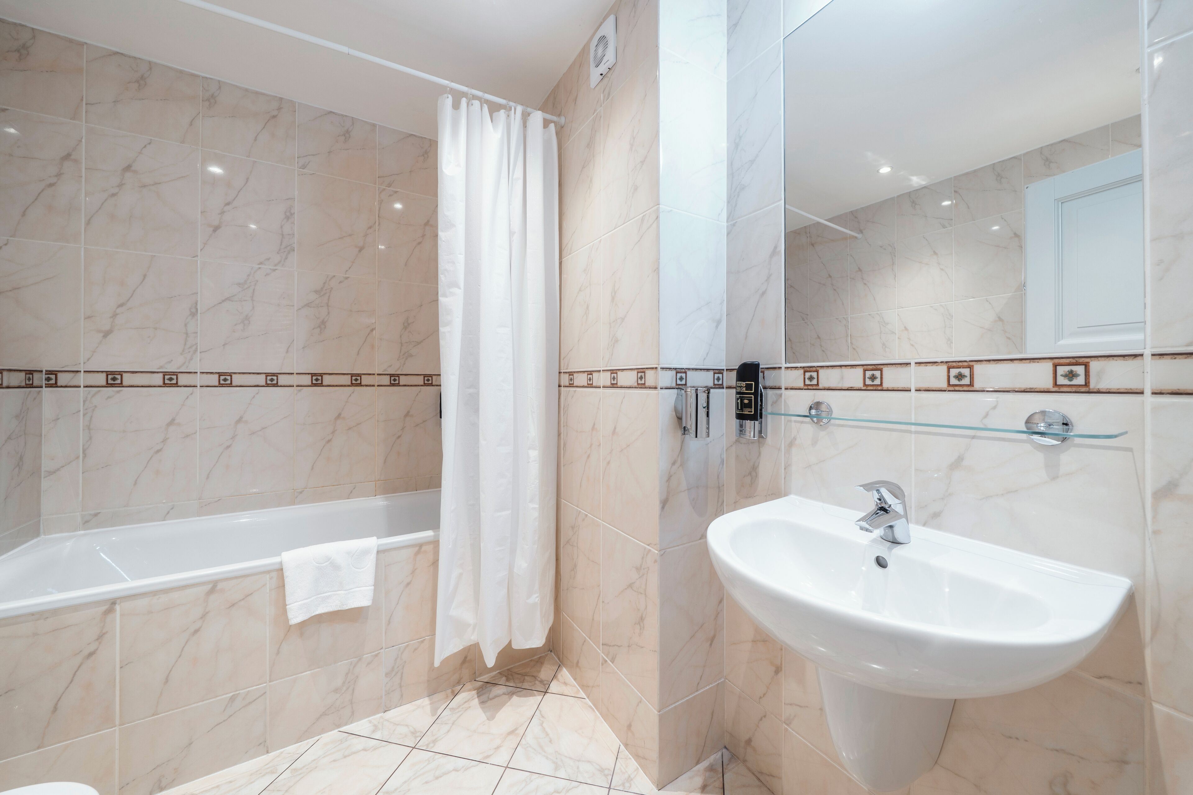 Une salle de bain avec une baignoire, un lavabo et un rideau de douche.