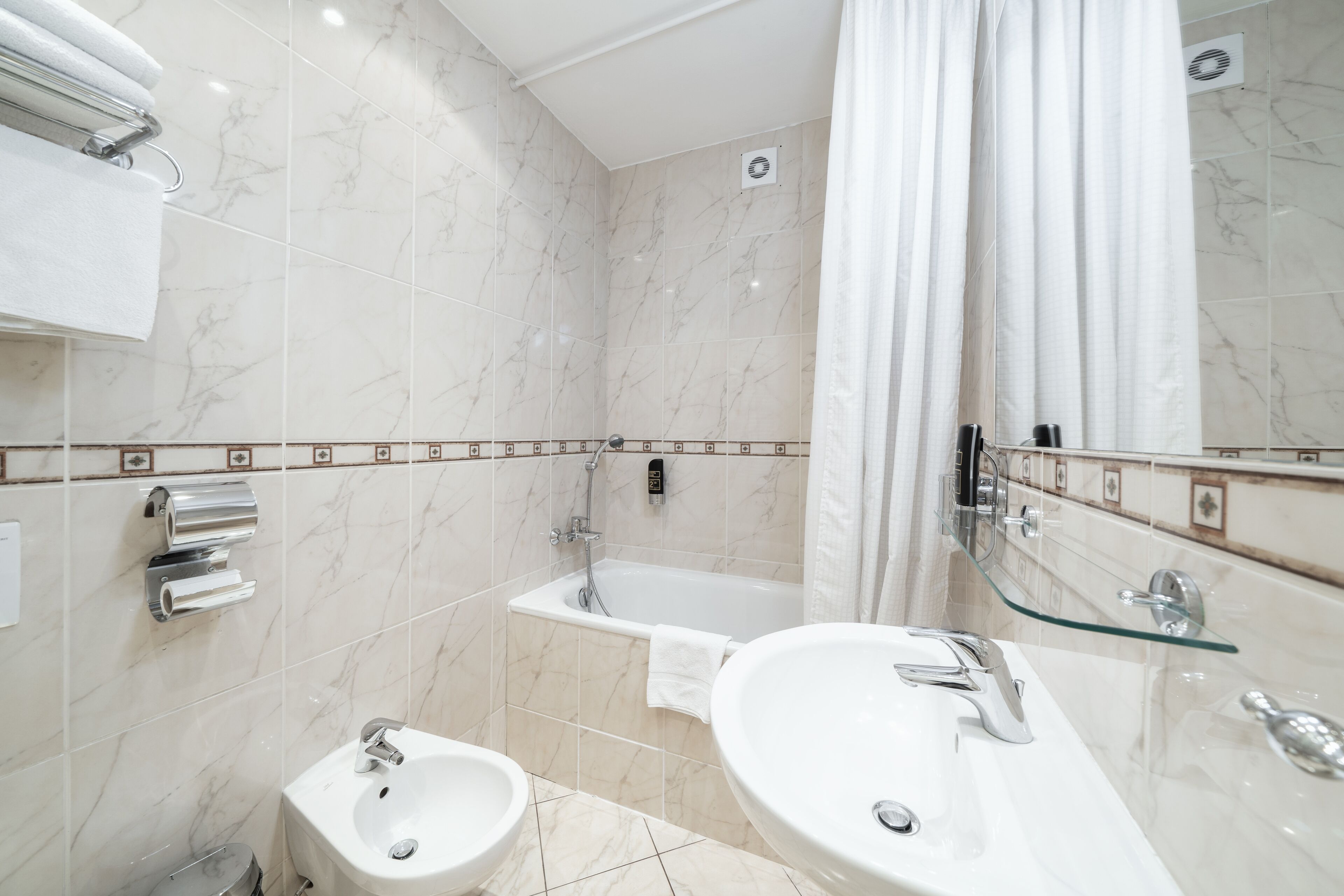 A modern bathroom with two sinks, a bathtub, and a glass shower enclosure.