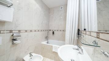 A modern bathroom with two sinks, a bathtub, and a glass shower enclosure.
