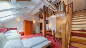 A spacious bedroom with a large bed, a desk, and a staircase. - Hotel Raffaello Prague (Prague)