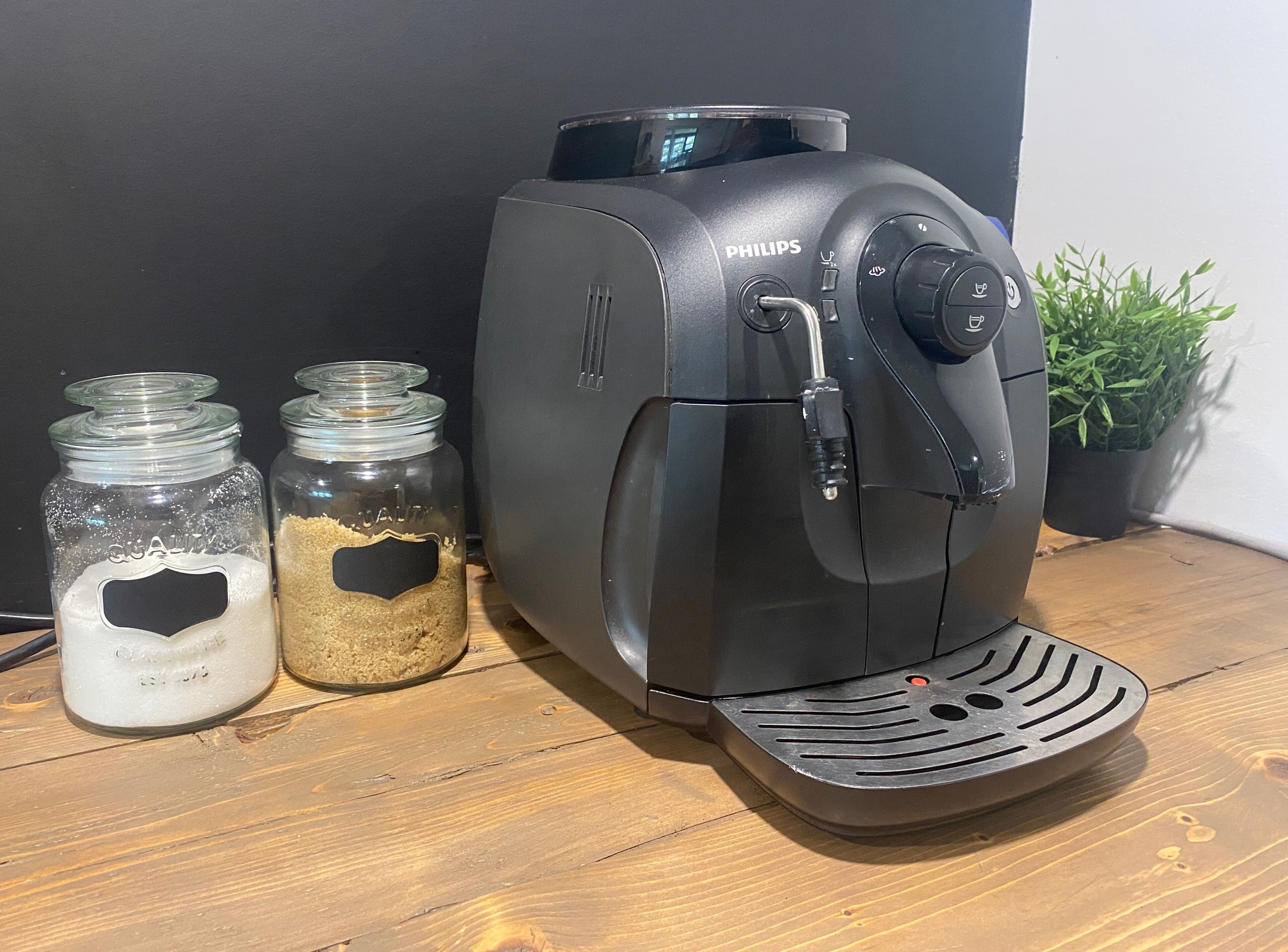 Une machine à café dotée de deux récipients en verre contenant du café moulu et du lait.