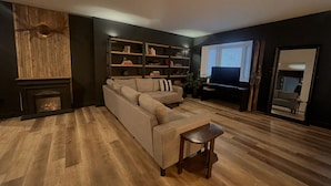 Una sala de estar moderna con un sofá modular, una chimenea, un televisor y una estantería.