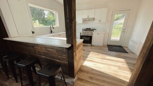 Una cocina moderna con una isla central, taburetes de bar y vistas al exterior.