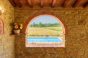 Un muro de piedra con un arco de ladrillo que da a una piscina.