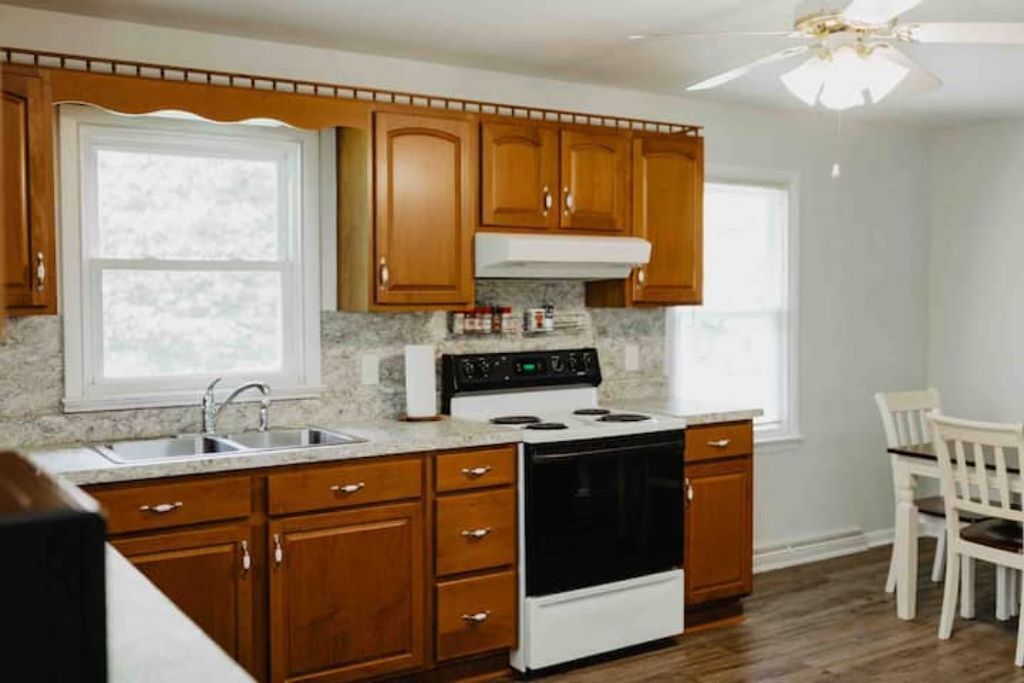 A kitchen with wooden cabinets, a white stove, and a window.