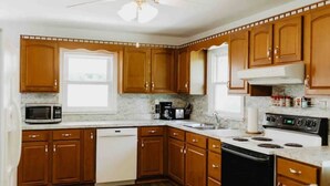 A kitchen with wooden cabinets, a microwave, a stove, and a dishwasher. - Rancher in Mont Alto (Mont Alto)